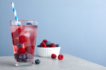 Delicious berry lemonade made with soda water on grey marble table. Space for text