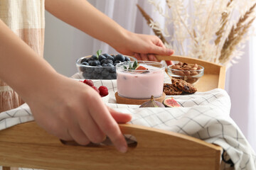 Woman holding wooden tray with delicious breakfast and fig smoothie, closeup