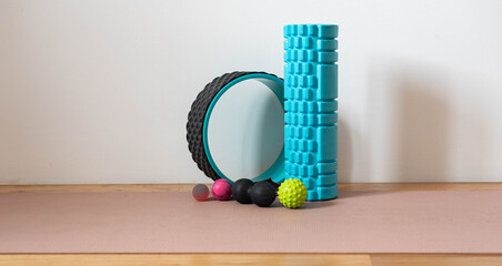 SMR roller and balls - fitness tools on wooden floor with a pink yoga mat (self-myofascial release)