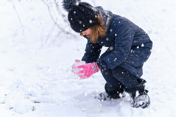 child girl playing with snow in winter outdoor and having fun on snowy winter