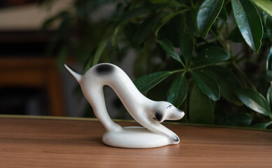 Mid century modern ceramic figurine - stretching dog on a wooden table, with plants