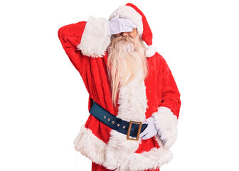 Old senior man with grey hair and long beard wearing traditional santa claus costume smiling and laughing with hand on face covering eyes for surprise. blind concept.