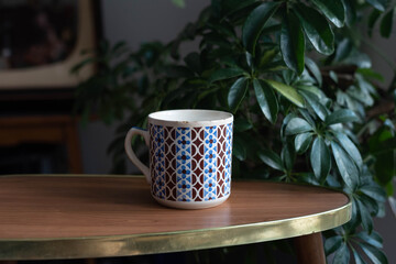 Mid century modern design coffee cup with abstract pattern on a wooden table with plants