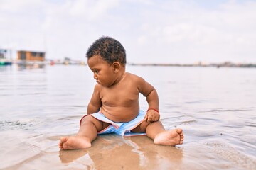 Adorable african american toddler sitting at the beach.