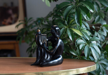 Mid century modern porcelain figurine - woman with a lyre on a wooden table, in the background plant