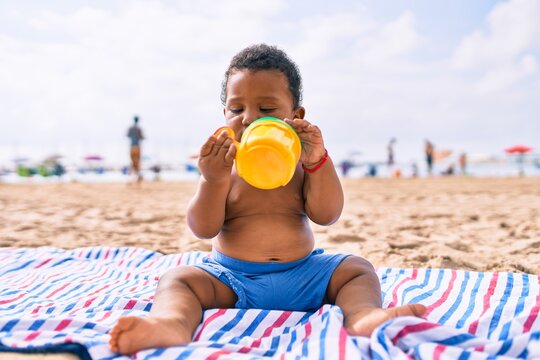 Adorable african american toddler playing with toys sitting on the sand at the beach.