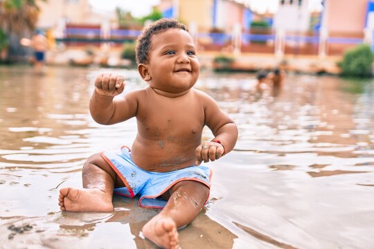 Adorable african american toddler smiling happy sitting at the beach.