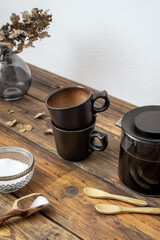 Zwei braune Tassen und eine Kaffeekanne auf einem rustikalen Holz Tisch. Frühstück, Retro, Zuhause.