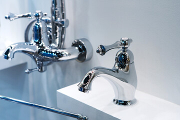 Chrome washbasin faucets in a plumbing shop. Trade in modern bathroom accessories