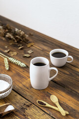 Gedeckter Kaffeetisch mit weißen Tassen und eine Schüssel mit Zucker auf einem Holz Tisch. Rustikaler Stil, weiße Wand, Zuhause. 