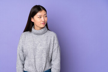 Young asian woman over isolated background having doubts while looking side