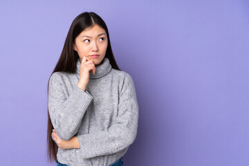 Young asian woman over isolated background having doubts and thinking