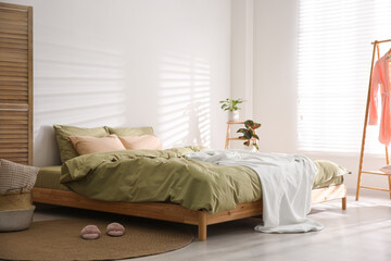 Fototapeta na wymiar Large bed with soft blanket in stylish room interior