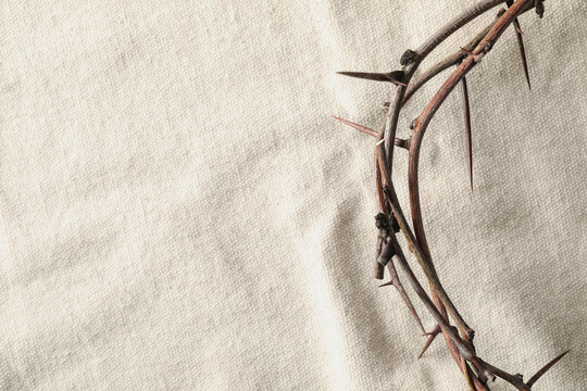 Crown of thorns on white fabric, top view with space for text. Easter attribute