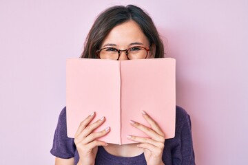 Young beautiful woman wearing glasses reading book smiling with a happy and cool smile on face....