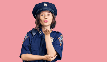 Young beautiful girl wearing police uniform looking at the camera blowing a kiss with hand on air being lovely and sexy. love expression.