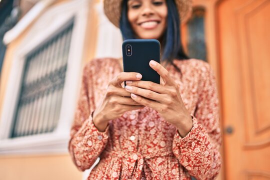 Young african american tourist woman on vacation smiling happy using smartphone at the city.