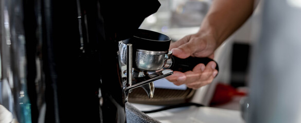 A male barista is making coffee from a machine. He's making lattes for customers.