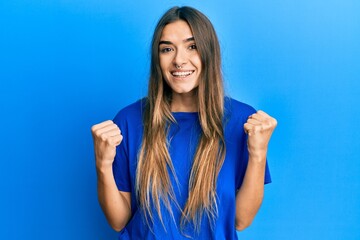 Fototapeta premium Young hispanic woman wearing casual clothes celebrating surprised and amazed for success with arms raised and open eyes. winner concept.
