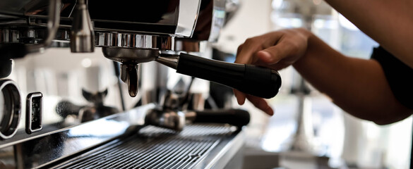 A male barista is making coffee from a machine. He's making lattes for customers.