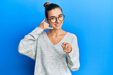 Young hispanic woman wearing casual clothes smiling doing talking on the telephone gesture and...