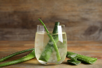 Fresh aloe drink with leaves in glass on wooden table