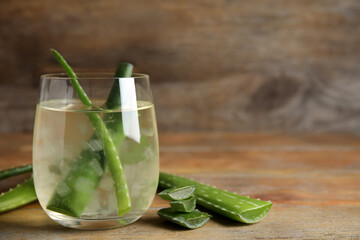 Fresh aloe drink with leaves in glass on wooden table. Space for text