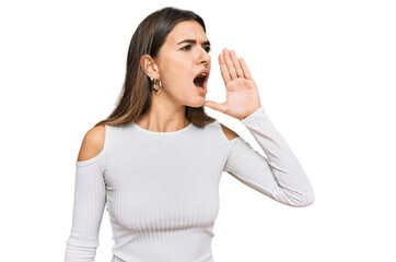Young hispanic woman wearing casual clothes shouting and screaming loud to side with hand on mouth. communication concept.
