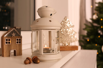 Decorative Christmas lantern with burning candle on windowsill
