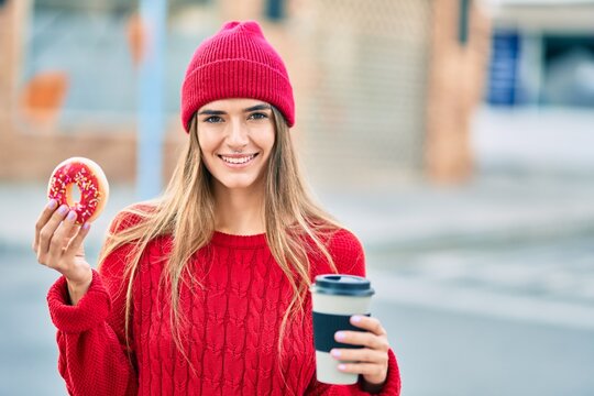 Young hispanic woman wearing wool cap having breakfast at the city.