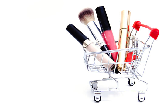 Shopping cart with cosmetics on white background