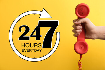 24/7 hotline service. Woman holding handset on yellow background, closeup