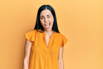 Beautiful young woman wearing casual clothes winking looking at the camera with sexy expression,...