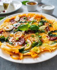 Delicious breakfast - scrambled eggs with onion and chorizo on wooden table