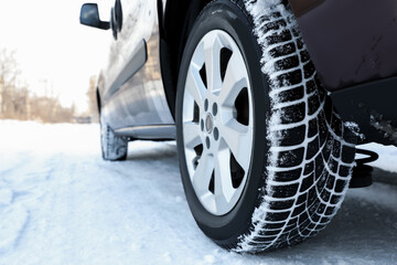 Car with winter tires on snowy road, closeup view