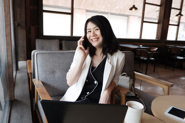 Smiling Asian businesswoman is is calling with smartphone online working in social media at workplace in modern office or relaxing at coffee shop. Lifstyle of people with techonology concept.