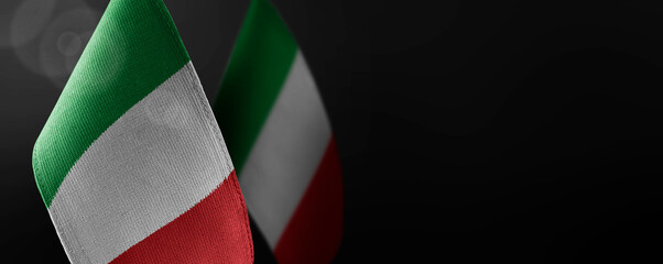 Small national flags of the Italy on a dark background