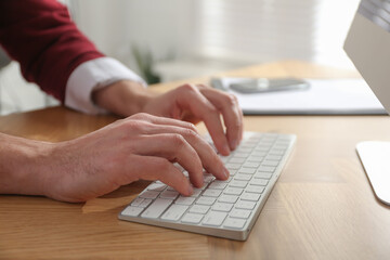 Freelancer working on computer at table indoors, closeup
