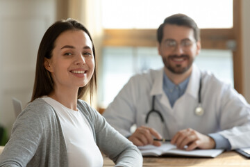 Happy millennial Caucasian female patient feel satisfied pleased with good hospital medical service after consultation with doctor. Portrait of smiling woman client consult with GP in private clinic.