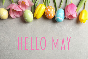 Hello May. Flat lay composition of painted Easter eggs and spring flowers on grey background © New Africa