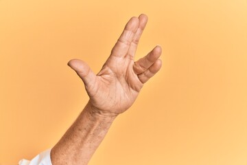 Senior caucasian hand over yellow isolated background greeting doing vulcan salute, showing hand palm and fingers, freak culture