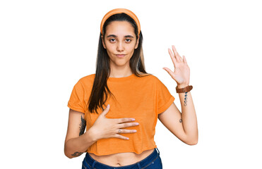Young hispanic woman wearing casual clothes swearing with hand on chest and open palm, making a...