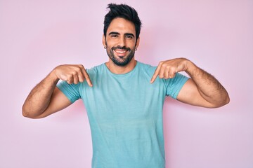 Handsome hispanic man with beard wearing casual clothes looking confident with smile on face, pointing oneself with fingers proud and happy.