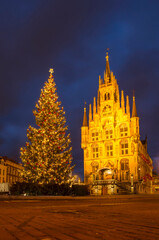Fototapeta na wymiar Gouda, The Netherlands, December 30, 2020 the market square in the holiday season, with a large Christmas tree next to the illuminated historic town hall