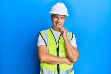 Middle age bald man wearing architect hardhat smiling looking confident at the camera with crossed arms and hand on chin. thinking positive.
