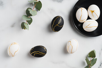 Luxury Easter eggs and eucalyptus leaves on marble table. Flat lay, top view. Minimal style.