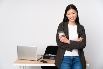 Business asian woman in her workplace isolated on white background keeping the arms crossed in...