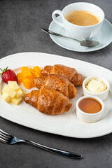 French croissant. Freshly baked croissants with honey and butter on dark stone background.