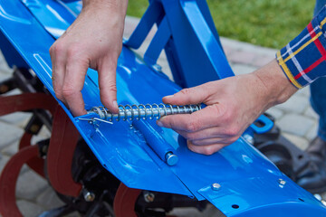install a spring on the mechanism,men's hands will install a spring on the cultivator housing for the tractor