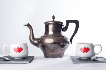 Teapot and two cups with hearts painted on them. Romantic tea time or breakfast. Concept of love and Valentines day   